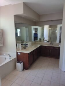 Spacious bathroom with a bathtub, large mirror, double sink vanity, tile floor, and glass shower enclosure; person visible taking the photo’s reflection in the mirror.
