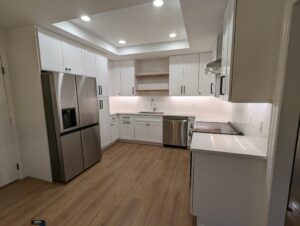 Modern kitchen with white cabinets, stainless steel appliances, wood flooring, subway tile backsplash, and recessed ceiling lights.